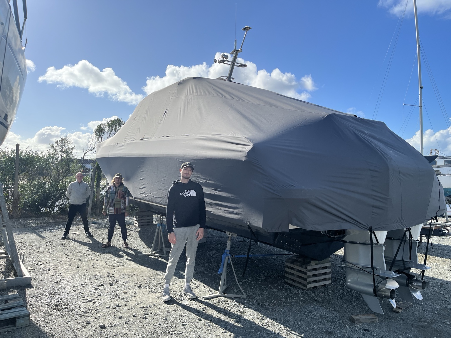 Finished grey all-over boat cover with three team members standing alongside to show its scale